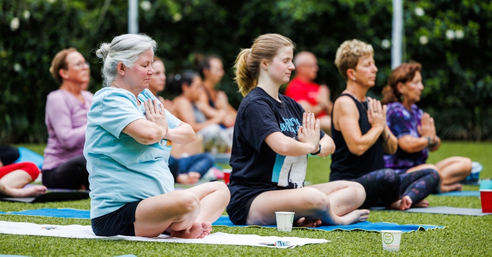 People practicing yoga poses on the Wedding Lawn at Sunken Gardens.